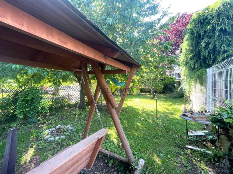 Záhrada s drevenou hojdačkou a stolom, Nemocničná ulica, Galanta, okolo bujná zeleň.
