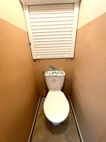 Toaleta s dlažbou, kombi WC a žalúziou v 2-izbovom byte.