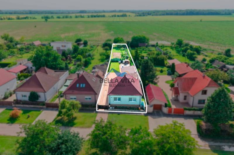 Rodinný dom na Hodskej ulici v Galante, obklopený záhradou a poľami v pozadí.