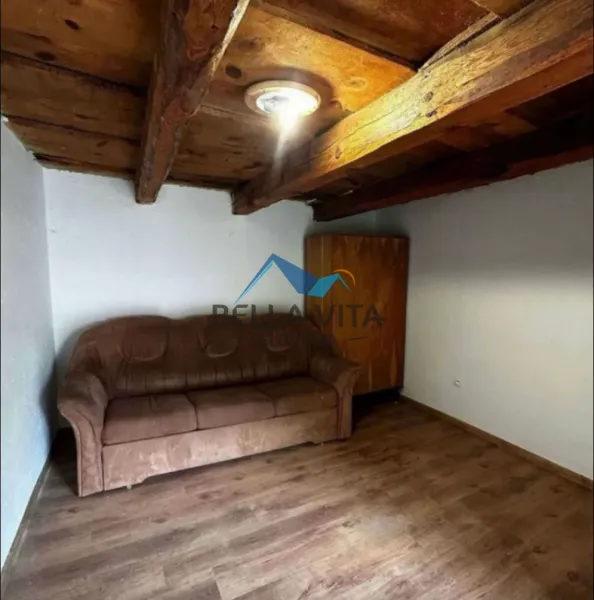 Drevený strop s hnedým gaučom a tmavou podlahou v rodinnom dome.