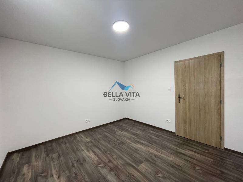 Izba s drevenou podlahou a bielymi stenami v 4-izbovom byte.