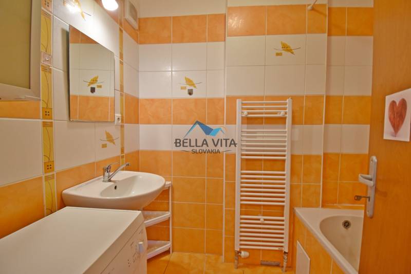 Kúpeľňa v 1-izbovom byte s oranžovými obkladačkami, umývadlom a vaňou.
