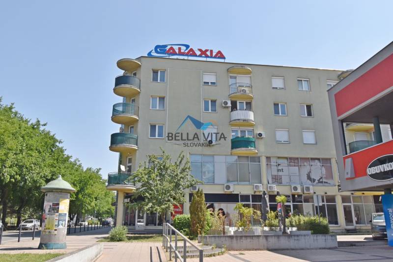 Budova na Hlavnej ulici v Galante s obchodnými priestormi a balkónmi.