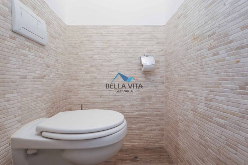 Toaleta v 3-izbovom byte s elegantnými obkladmi a podlahou s dreveným dekorom.