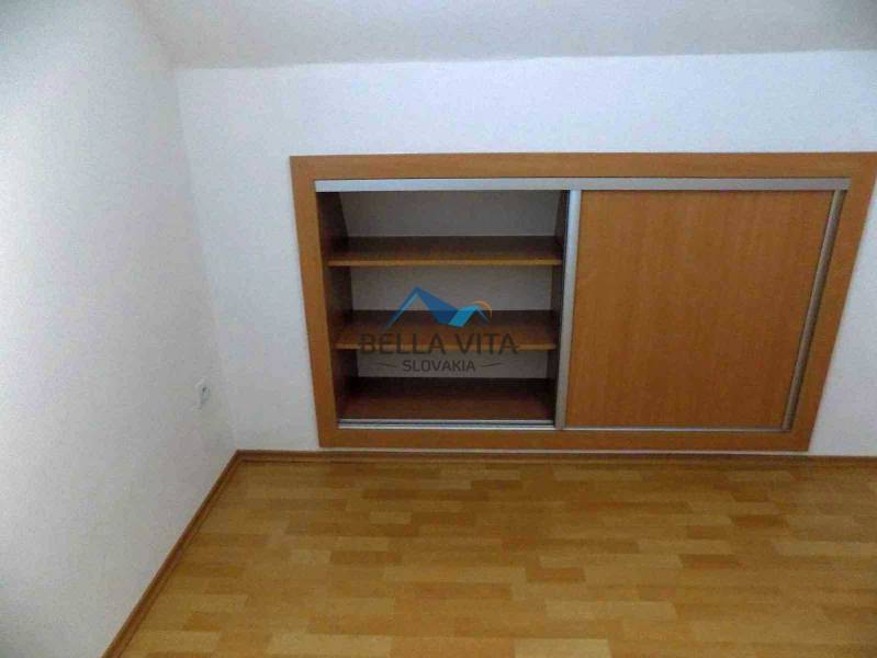 Úložný priestor s posuvnými dverami a podlahou s dreveným dekorom v 2-izbovom byte.