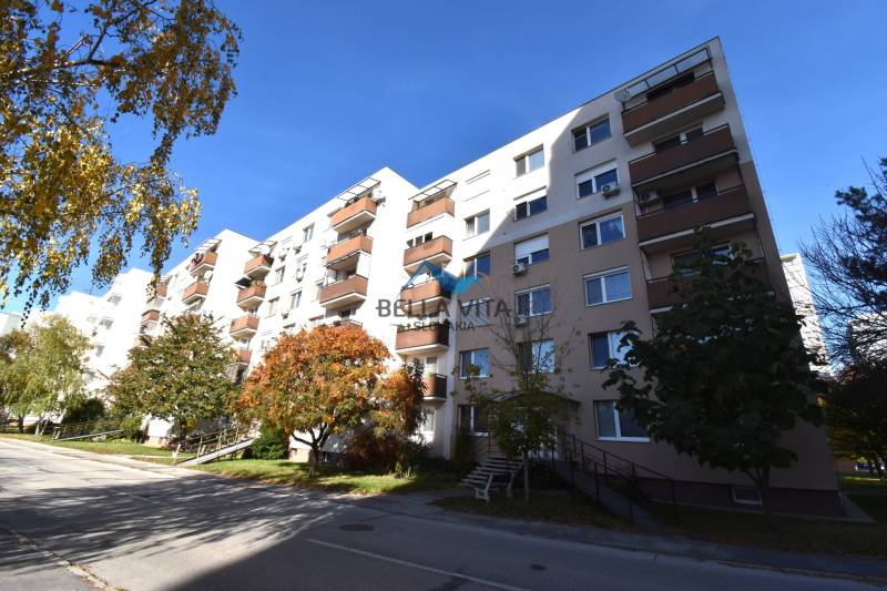 Bytový dom na Štvrti SNP v Galante obklopený stromami a modrou oblohou.