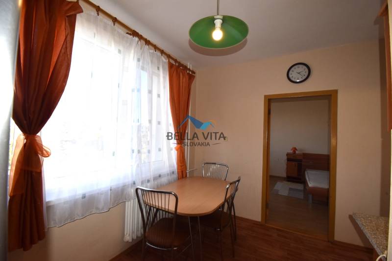 Jedálenský kút s oknom, závesmi, stolom a kovovými stoličkami v 2-izbovom byte.