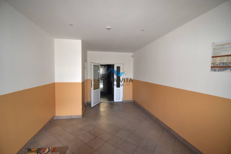 Chodba so svetlými dlaždicami a bielooranžovými stenami, dvojkrídlové dvere v 2-izbovom byte.