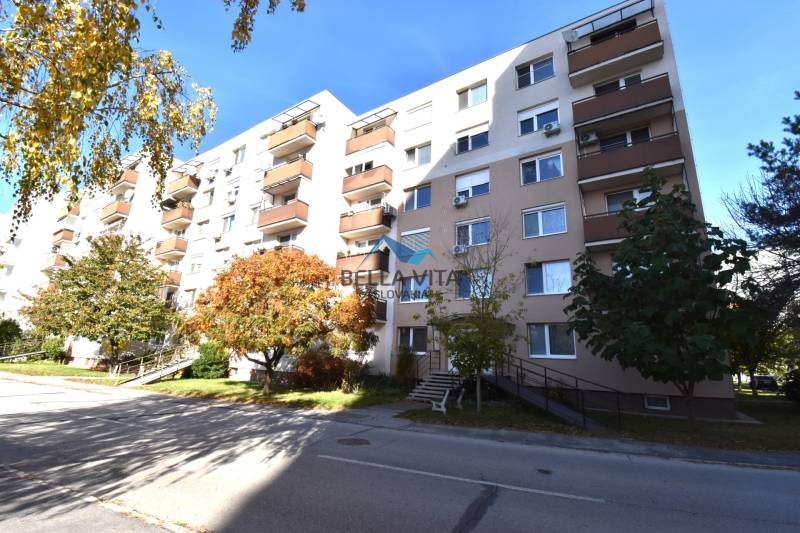 Bytový dom na Štvrti SNP v Galante obklopený stromami a jasnou oblohou.