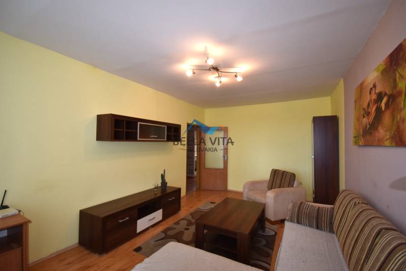 Obývacia izba s podlahou s dreveným dekorom, sedačkou a nábytkom v 2-izbovom byte.