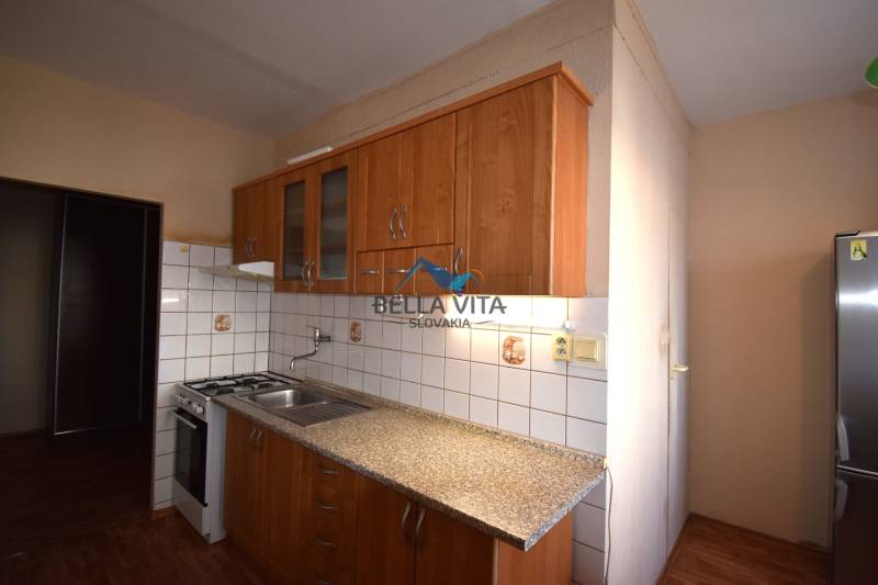 Kuchyňa v 2-izbovom byte s dreveným dekorom a kachličkami.