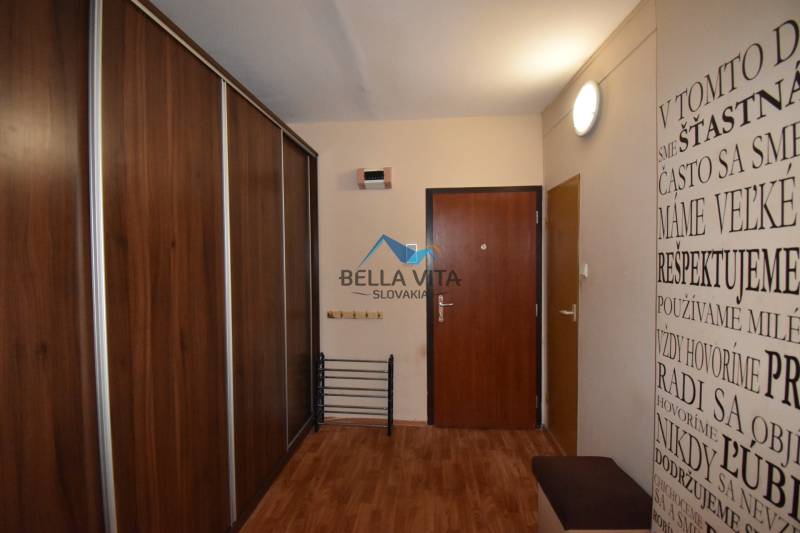 Vstupná chodba s podlahou s dreveným dekorom a nástennou potlačou v 2-izbovom byte.