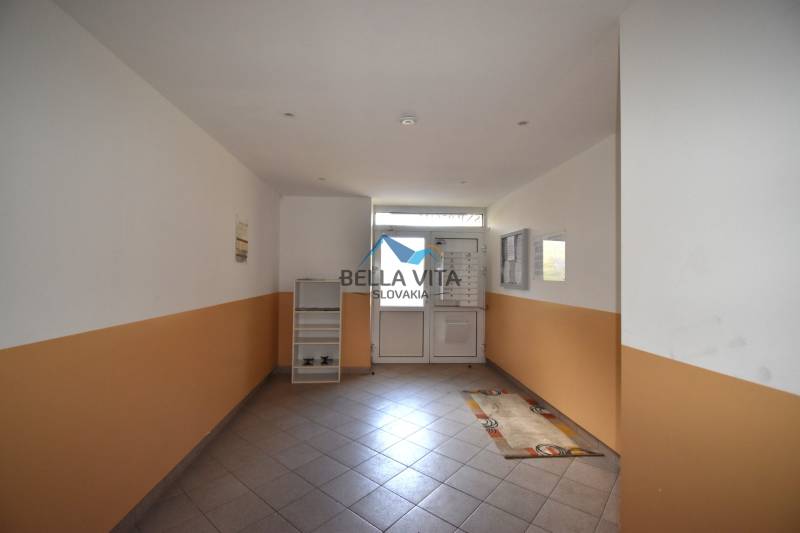 Chodba s bielooranžovými stenami a kachličkovou podlahou v 2-izbovom byte.