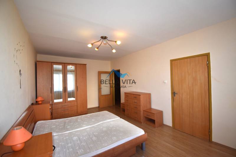 Spálňa so skriňou a dreveným dekorom v 2-izbovom byte.