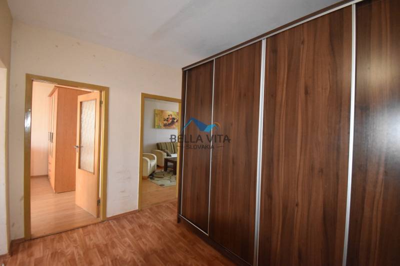 Chodba s veľkou skriňou, podlaha s dreveným dekorom, prechod do obývačky.