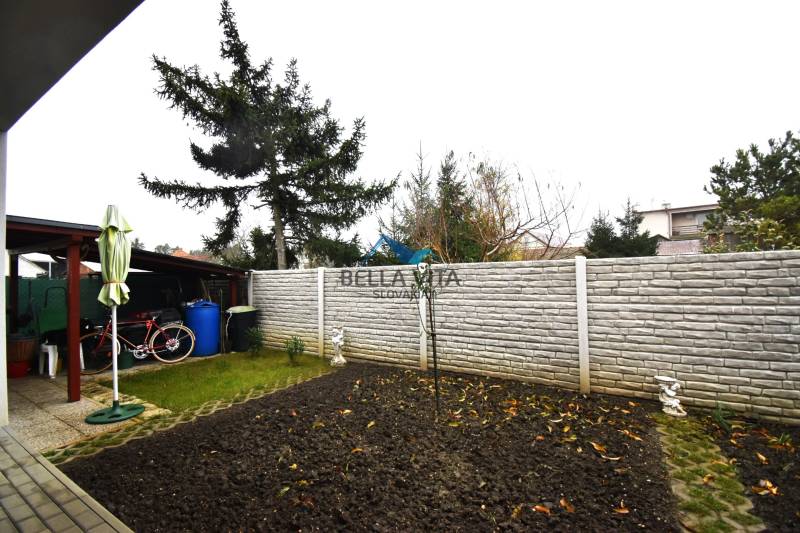 Záhrada rodinného domu na Hlavnej ulici v Mostovej s altánkom a stromami.