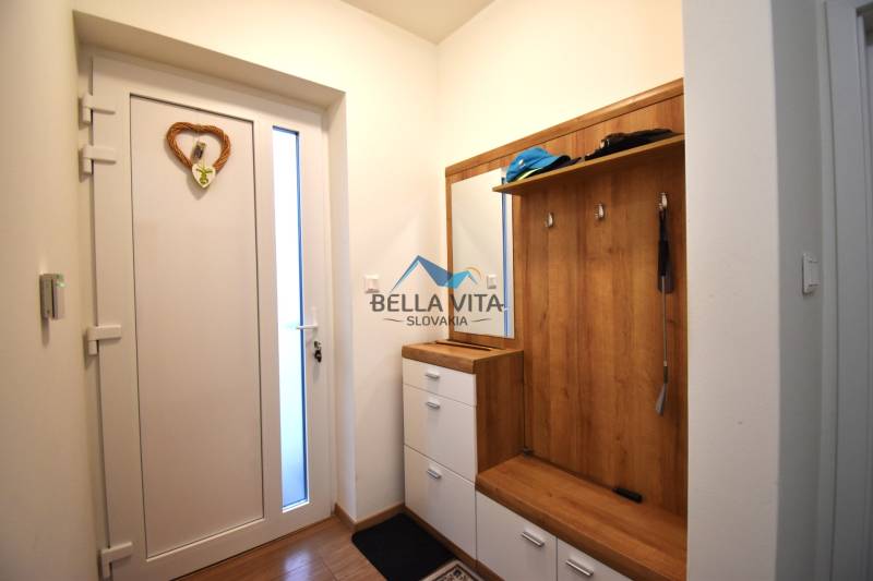 Vstupná hala v rodinnom dome s vešiakom a skrinkou, podlaha s dreveným dekorom.