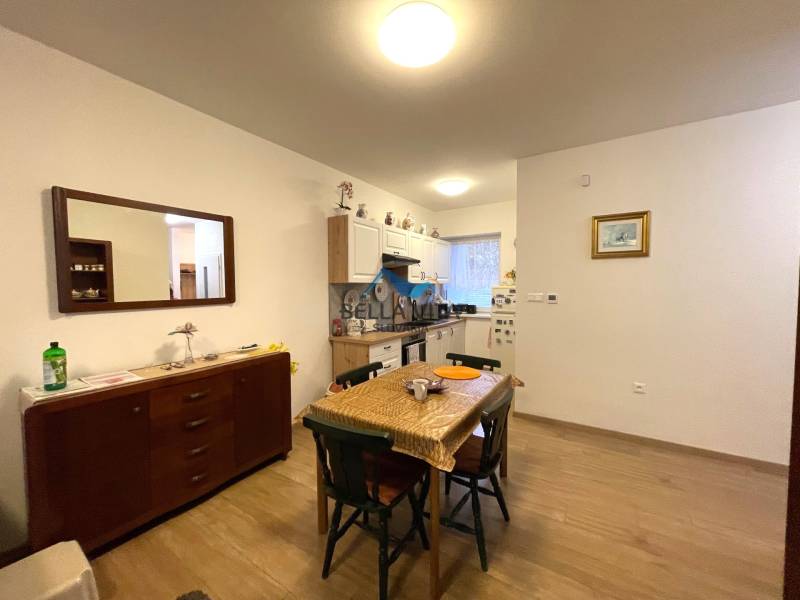 Jedáleň v rodinnom dome s rozkladacím stolom, skrinkou a podlahou s dreveným dekorom.