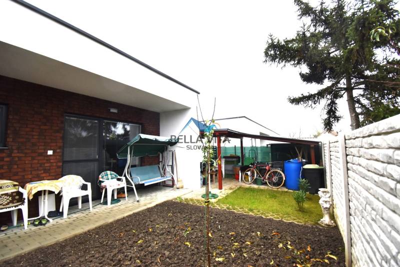 Záhrada rodinného domu na Hlavnej ulici v Mostovej s terasou a záhradným nábytkom.