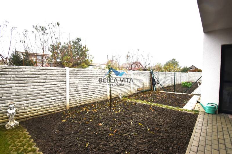 Záhrada rodinného domu na Hlavnej ulici v Mostovej s úrodnou pôdou a drevinami.