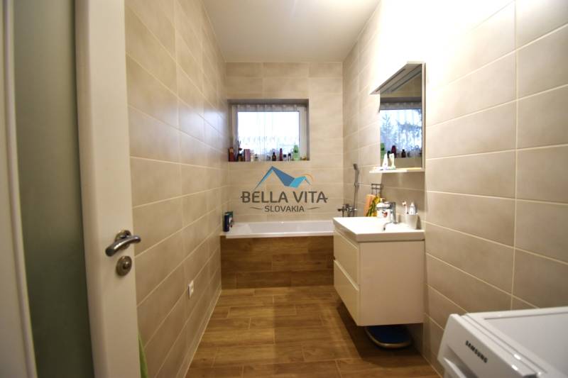 Kúpeľňa v rodinnom dome s vaňou a podlahou s dreveným dekorom.