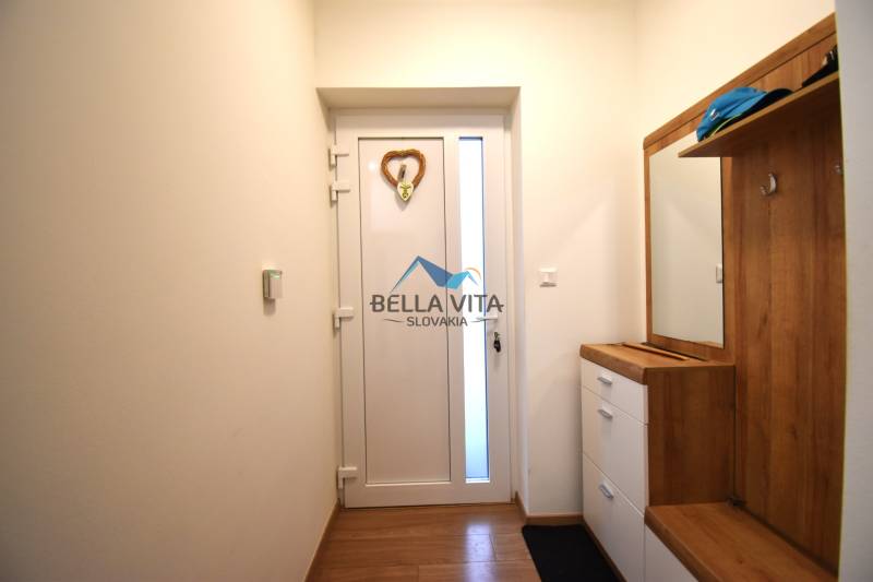 Vstupná chodba v rodinnom dome s bielymi dverami a podlahou s dreveným dekorom.