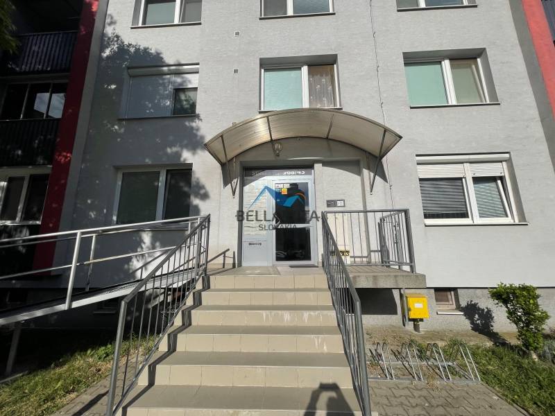 Vchod do bytového domu na Štvrti SNP v Galante s rampou a schodmi.