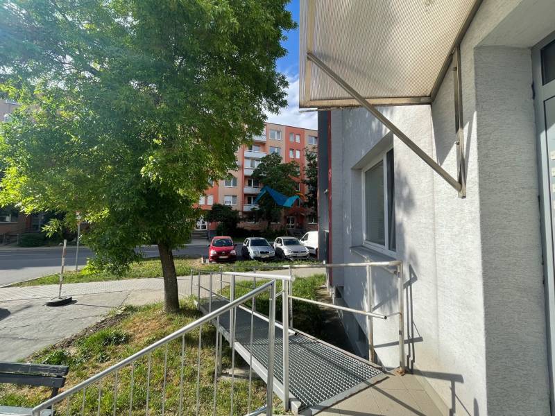 Exteriér budovy na Štvrti SNP v Galante, vedľa cesty s parkovaním áut.