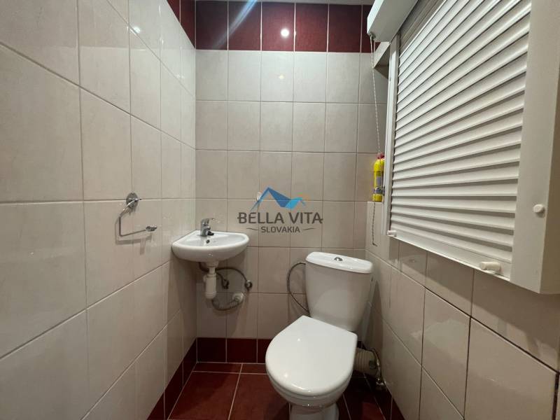 Toaleta v 2-izbovom byte s umývadlom a roletami na okne.