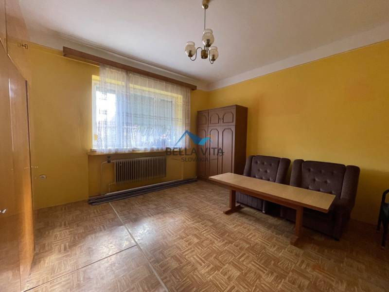 Žltá izba v rodinnom dome s dvomi kreslami a stolom, podlaha s dreveným dekorom.