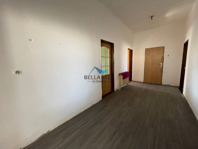 Interiér rodinného domu s podlahou s dreveným dekorom a bielymi stenami.