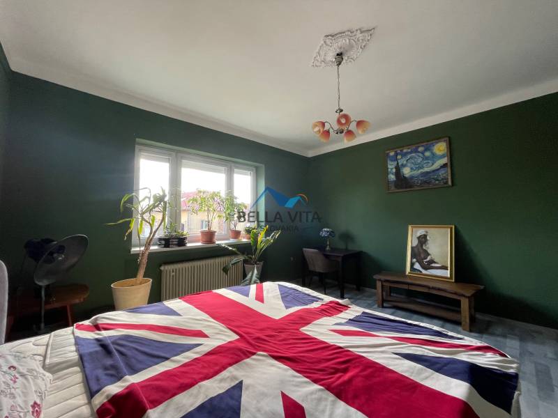 Spálňa v rodinnom dome s odvážnou dekoráciou v britskom štýle a zelené steny.