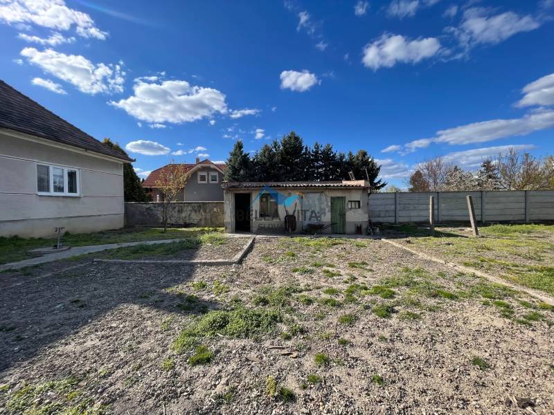 Záhrada pri rodinnom dome na ulici Heď v Čiernom Brode s nízkymi stavbami a plotom.