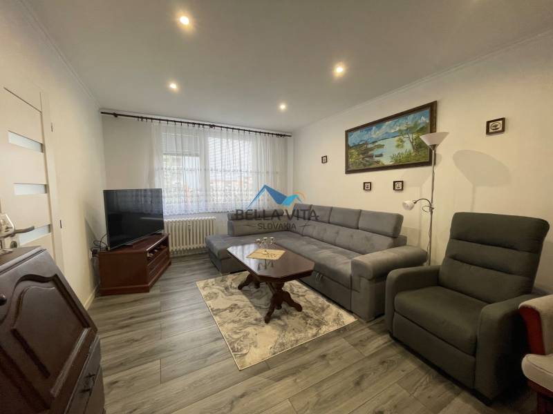 Obývacia izba s pohovkou, televízorom, kreslom a podlahou s dreveným dekorom v 3-izbovom byte.