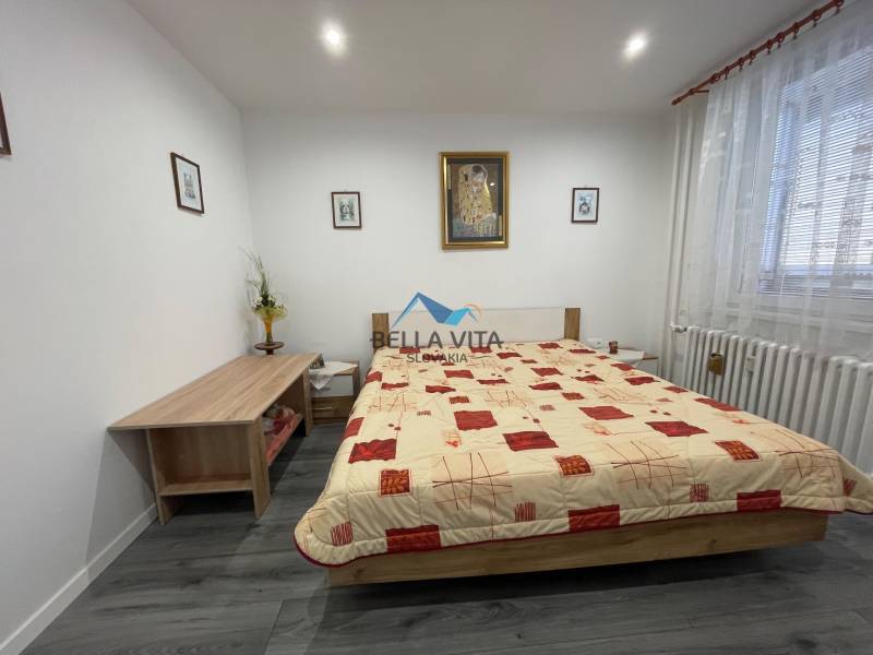 Spálňa s posteľou, podlahou s dreveným dekorom a komodou v 3-izbovom byte.