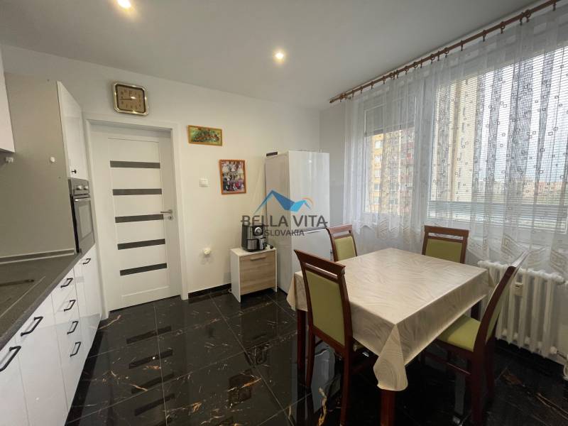 Moderná kuchyňa v 3-izbovom byte s bielymi skrinkami a jedálenským stolom.