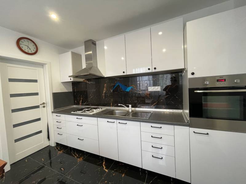 Kuchyňa v 3-izbovom byte s bielymi skrinkami a čiernym obkladom.