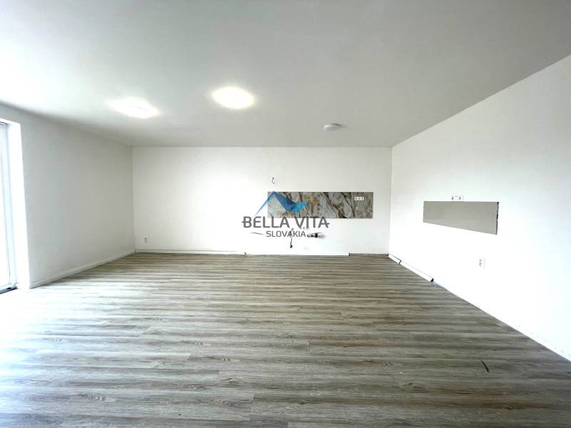 Interiér rodinného domu s podlahou s dreveným dekorom a bielymi stenami.