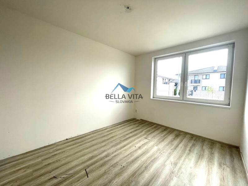 Izba v rodinnom dome so svetlými stenami a podlahou s dreveným dekorom.