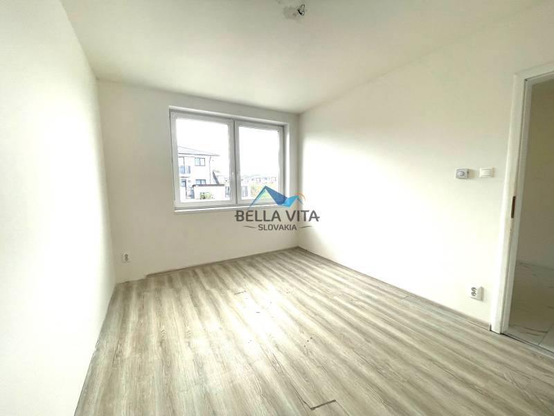 Prázdna izba s bielymi stenami a podlahou s dreveným dekorom v Rodinnom dome.