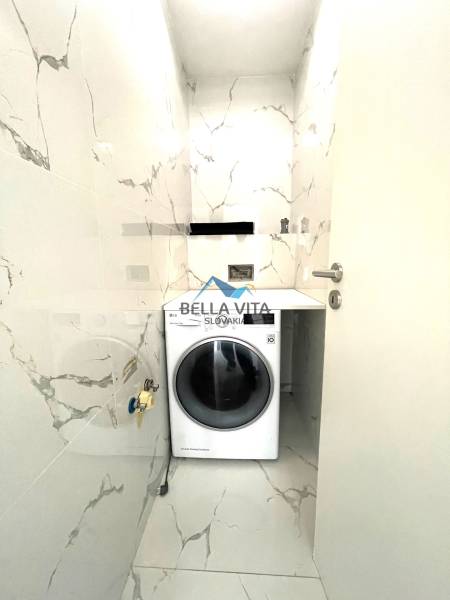 Práčovňa v rodinnom dome s mramorovým vzorom obkladu a práčkou.