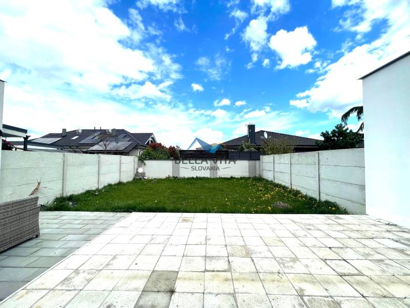 Záhrada rodinného domu v Ekoosade vo Veľkých Úľanoch s betónovým plotom a trávnikom.