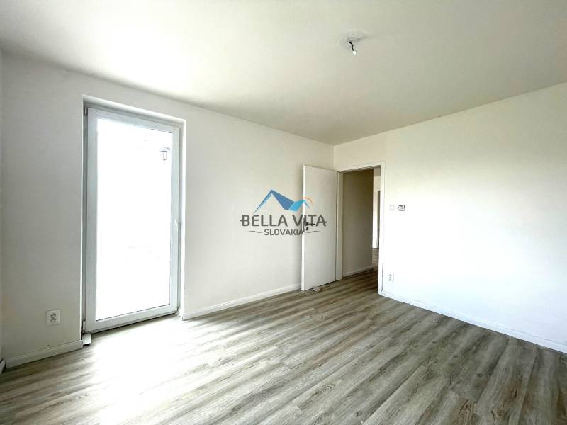 Priestranná izba s podlahou s dreveným dekorom a veľkým oknom v rodinnom dome.