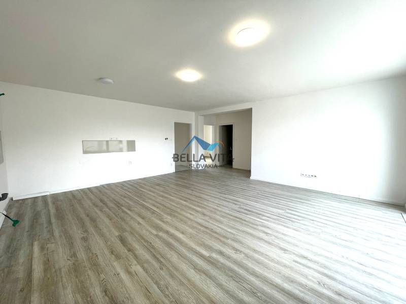 Priestranná izba v rodinnom dome s podlahou s dreveným dekorom a bielymi stenami.