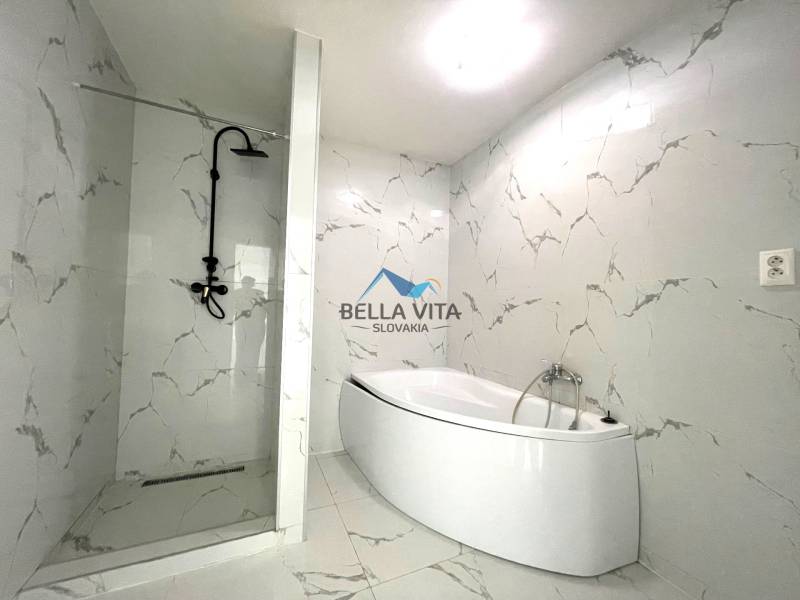Kúpeľňa v rodinnom dome s vaňou a sprchovým kútom, mramorové obklady.