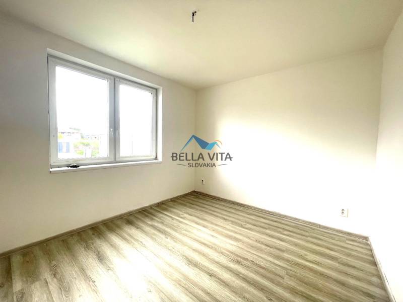 Izba s veľkým oknom a podlahou s dreveným dekorom v rodinnom dome.