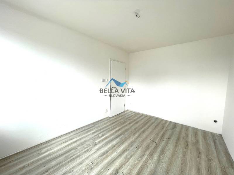 Izba v rodinnom dome s bielymi stenami a podlahou s dreveným dekorom.