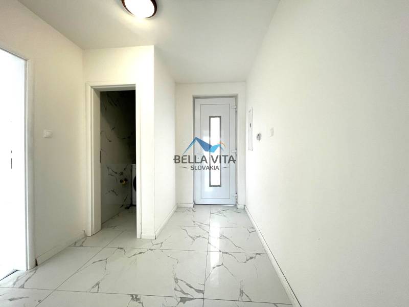 Chodba v rodinnom dome s bielymi stenami a podlahou s mramorovým dekorom.