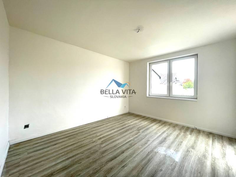 Priestranná miestnosť s podlahou s dreveným dekorom, veľkým oknom v rodinnom dome.