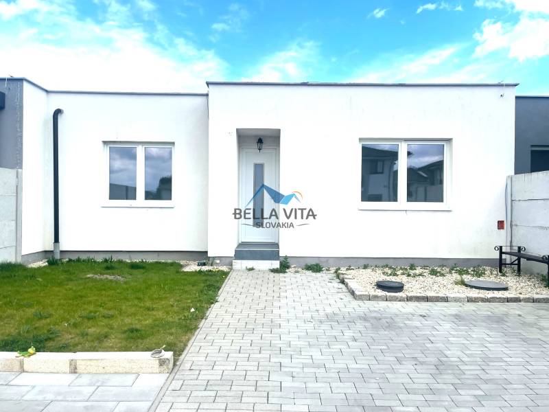 Rodinný dom v Ekoosade vo Veľkých Úľanoch s bielou fasádou a dláždenou terasou.